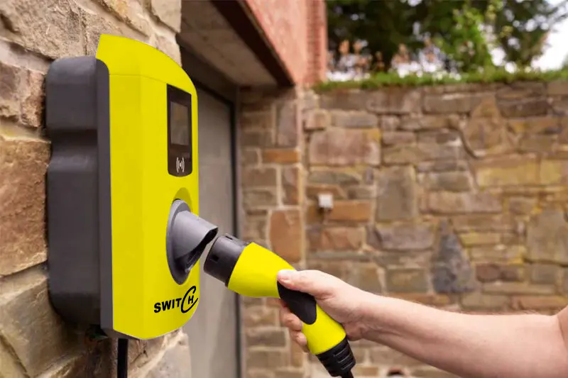 Main branchant un câble sur une borne de recharge Switch